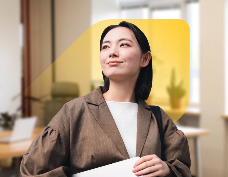 A photo of an Asian woman smiling proudly overlaid on an extended version of the EQ Bank jewel and a bright office space with various spotted plants