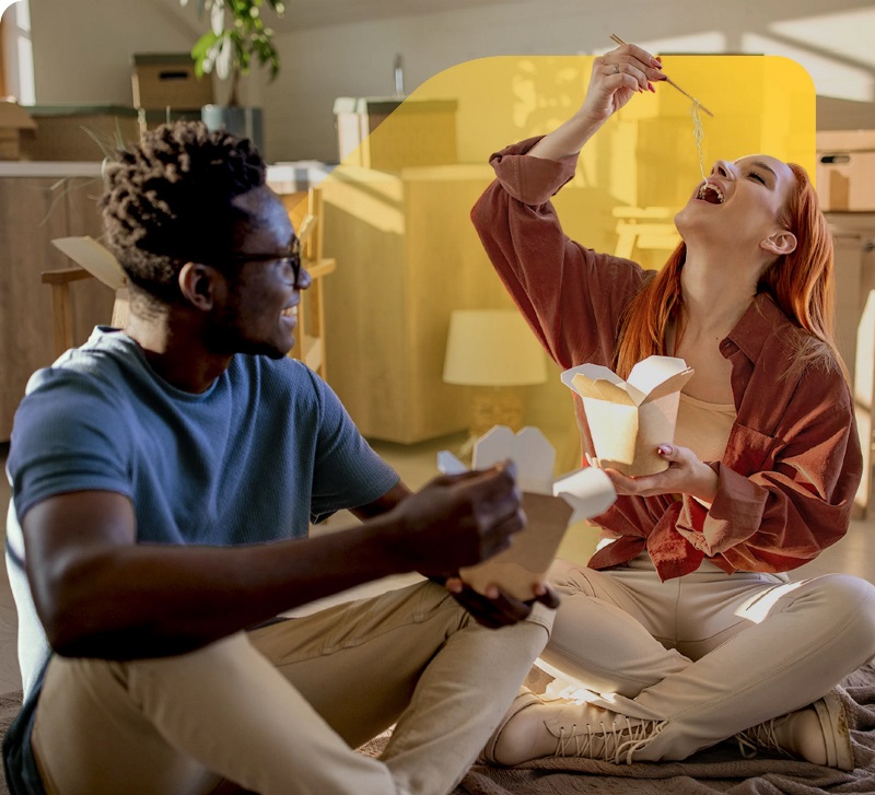 illustration d'une maison avec un signe vendu à l'extérieur. Une femme s'occupe du jardin et un homme transporte une boîte de déménagement dans les escaliers jusqu'à la maison.