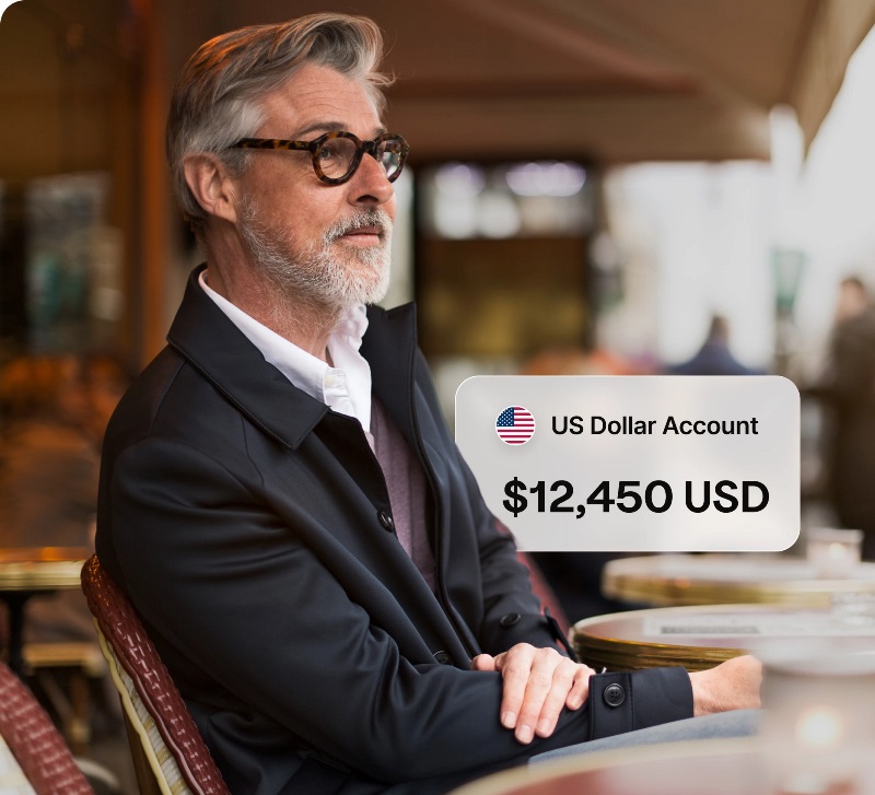man sitting at a table showing his US Dollar Account balance